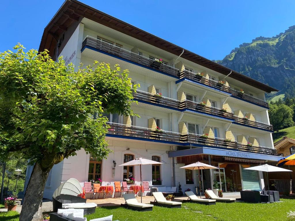 ein Hotel mit Stühlen und Sonnenschirmen davor in der Unterkunft Guest Rooms with a great view at Residence Brunner in Wengen