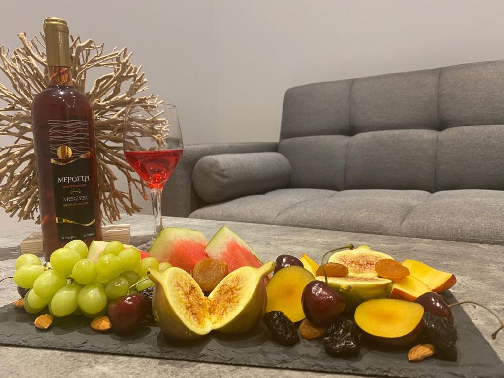 a tray of fruit on a table with a bottle of wine at Luxury Lavender in Larnaca