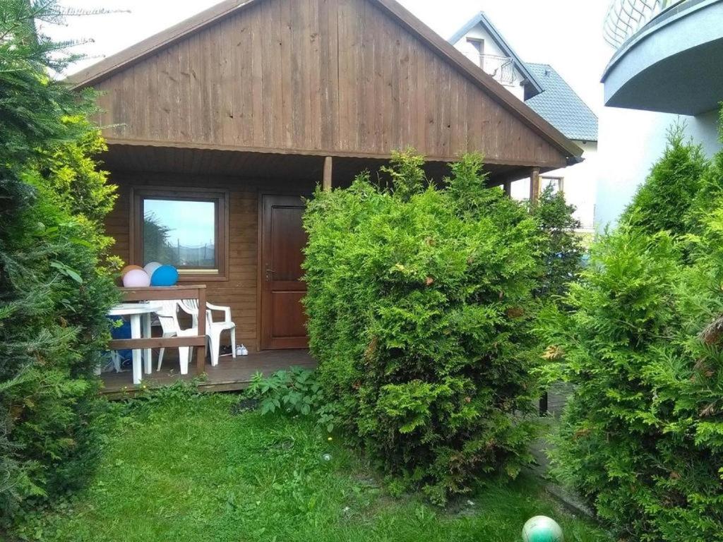 a wooden house with a table in the yard at Domek Muszelka in Karwia