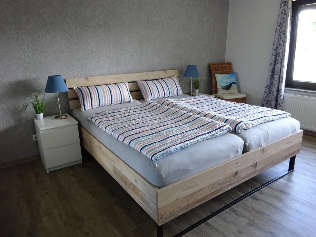 una camera da letto con un grande letto in legno con due cuscini di Ferienwohnung Schwiemann, Erdgeschoss a Cadenberge