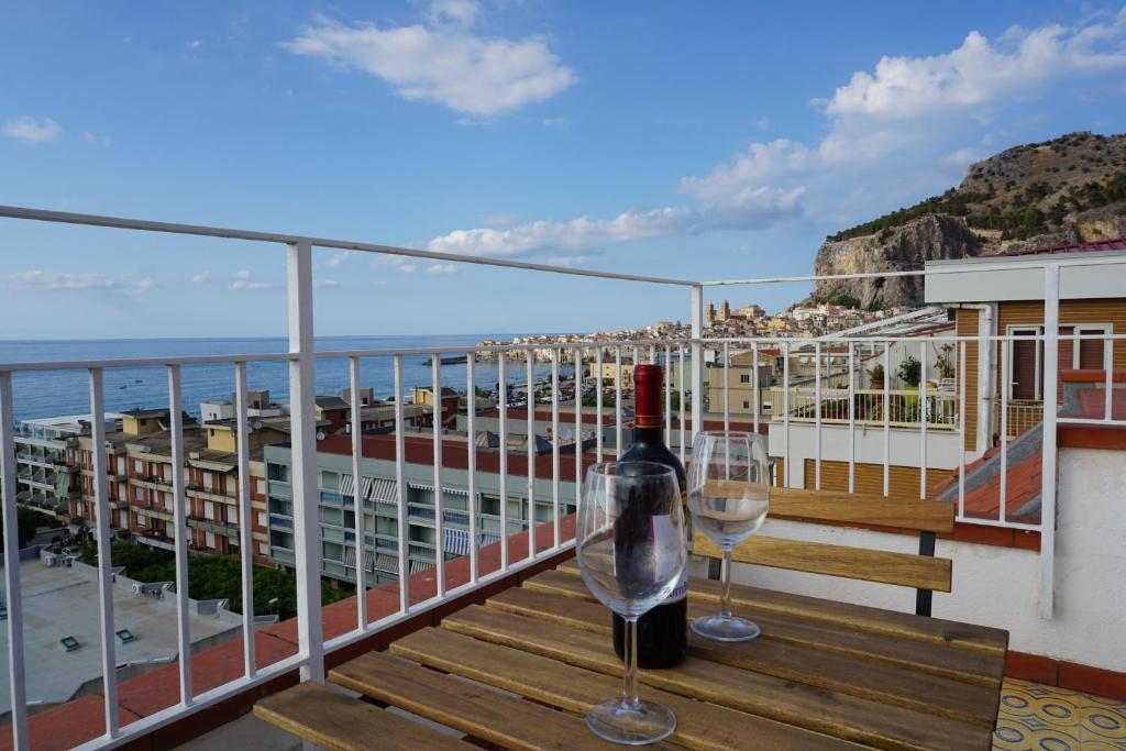 - une bouteille de vin et deux verres sur un balcon dans l'établissement Tinky's House, à Cefalù