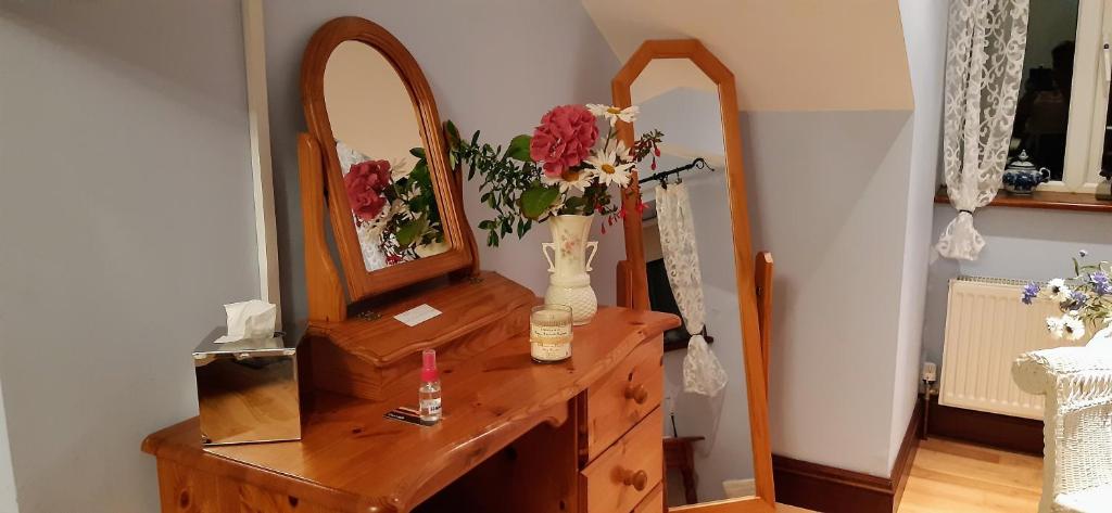 a dresser with a mirror and a vase with flowers on it at Creevagh (Room Only) in Keel