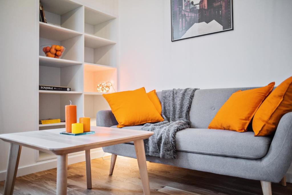 a living room with a gray couch with orange pillows at Best INN Poznań Apartament Orzeszkowej in Poznań