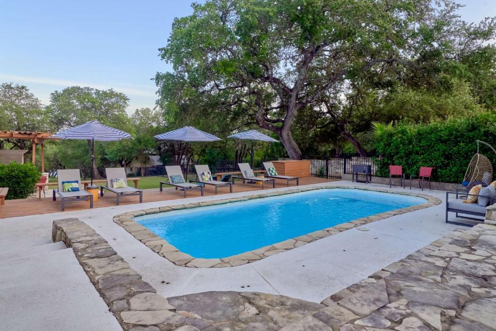 een zwembad met stoelen en parasols in een tuin bij Lake Travis Getaway on Hudson Bend in Austin