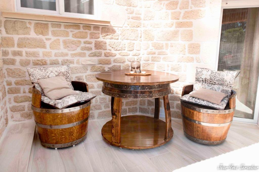 a table and two stools with a table and two barrels at Le Mas des Mathes, Chambres d&#39;hôtes, Studios in Les Mathes