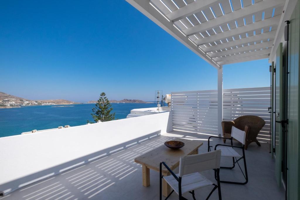un balcone con tavolo, sedie e acqua di Lorenzo Studios and Suites Paros a Naoussa