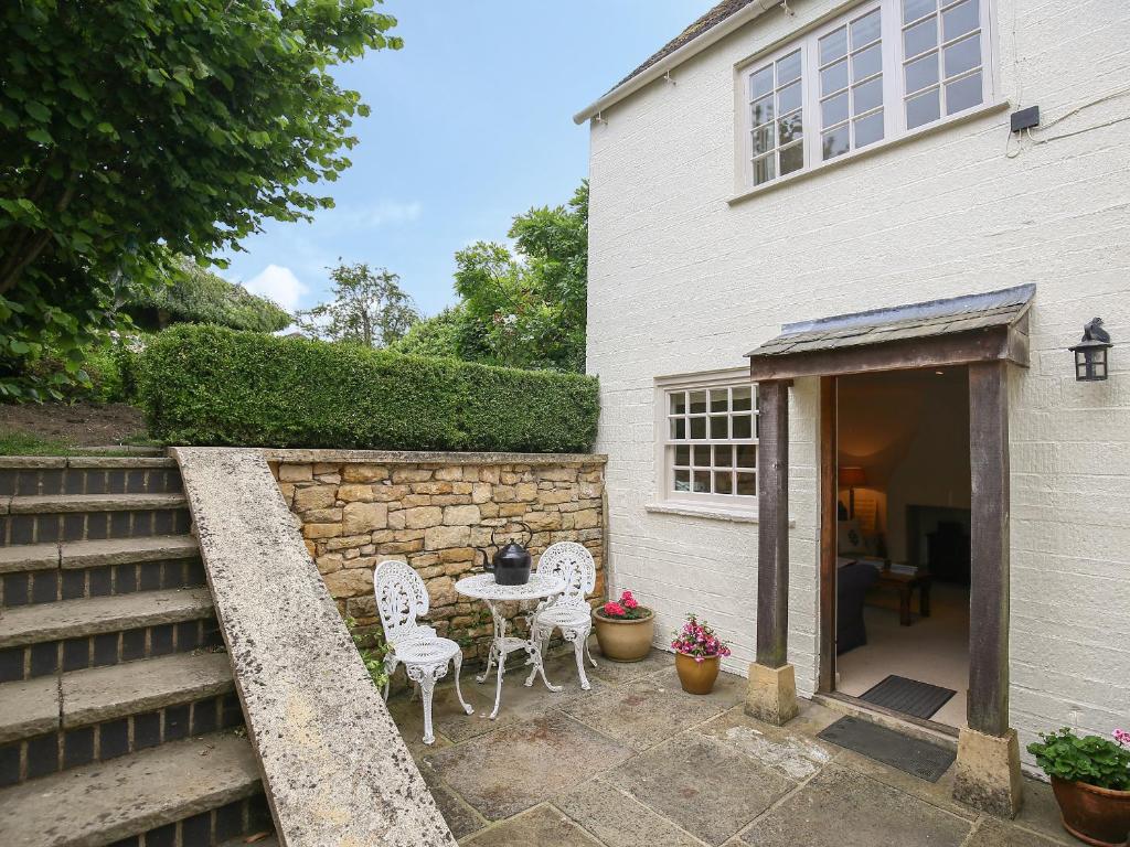 a patio with a table and chairs next to a building at Kettle Cottage in Chipping Campden