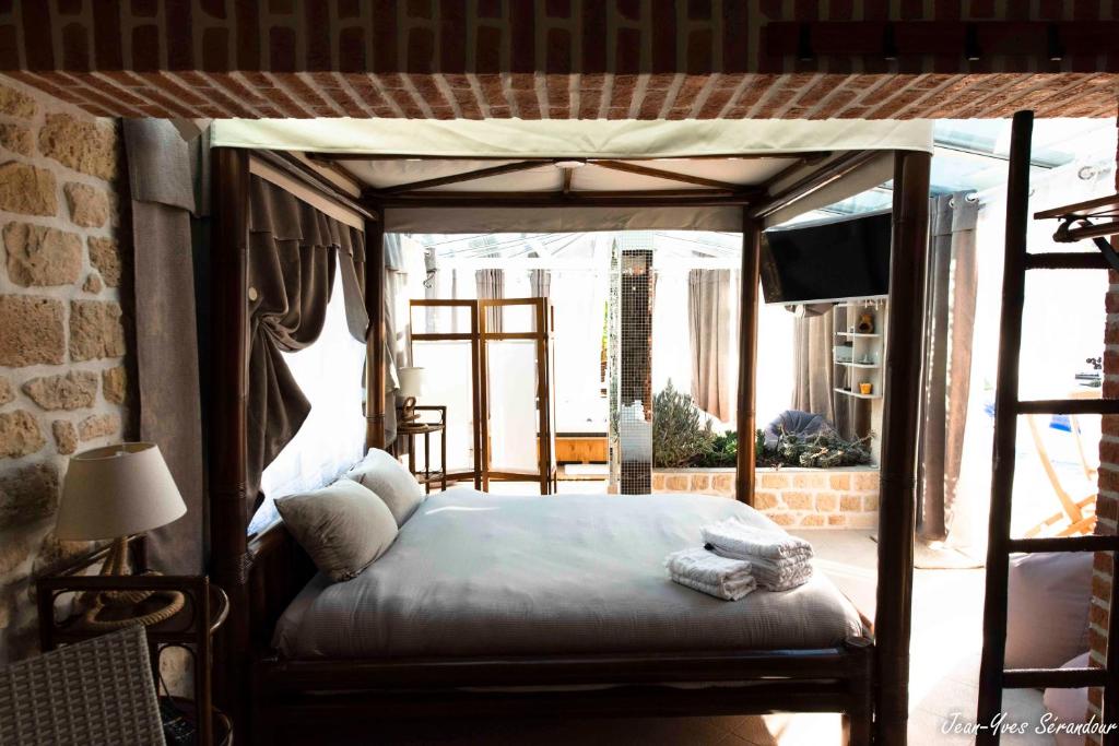 a bedroom with a canopy bed and a television at Le Mas des Mathes, Chambres d&#39;hôtes, Studios in Les Mathes