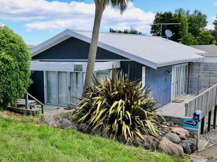a blue house with a palm tree in front of it at Harakeke House Upstairs - Ohakune Chalet in Ohakune