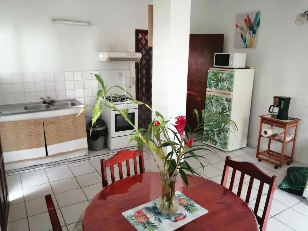une cuisine avec une table et un vase de fleurs. dans l'établissement Gite Belvédère Deshaies, à Deshaies
