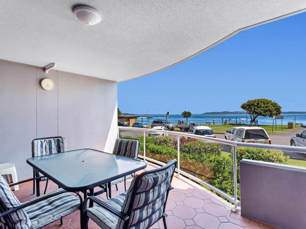 a balcony with a table and chairs and a view of the ocean at Florentine 2 sensational waterviews and pool in complex in Nelson Bay
