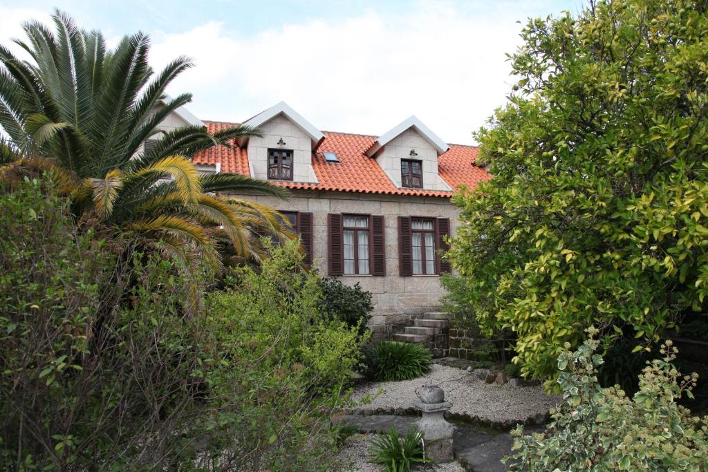een oud huis met een oranje dak en bomen bij Casa Cardoso in São Martinho de Mouros