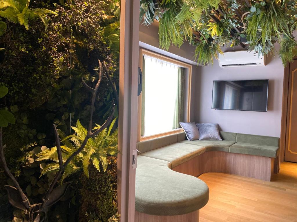 een kamer met een bank en een tv en planten bij THE WARDROBE Hotel Shimokitazawa in Tokyo