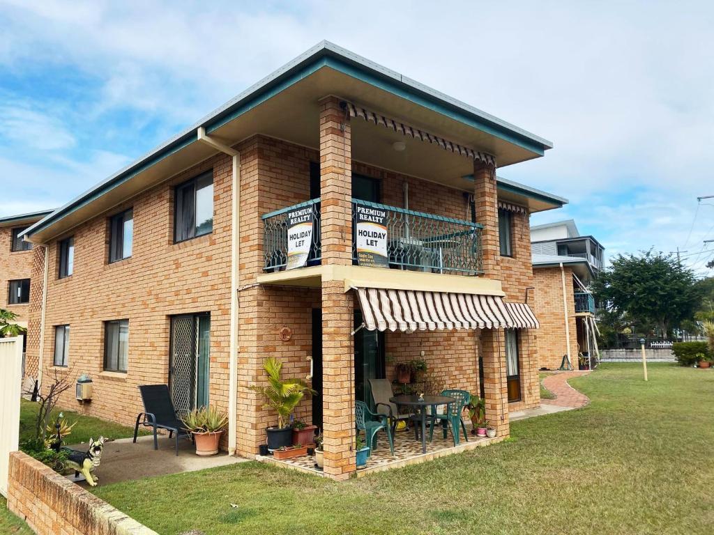 a brick house with a balcony with tables and chairs at Cloud 8 on Welsby in Bongaree
