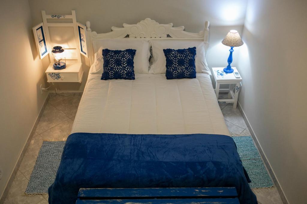 a bedroom with a large white bed with blue pillows at Pousada Rua de Lazer in Domingos Martins