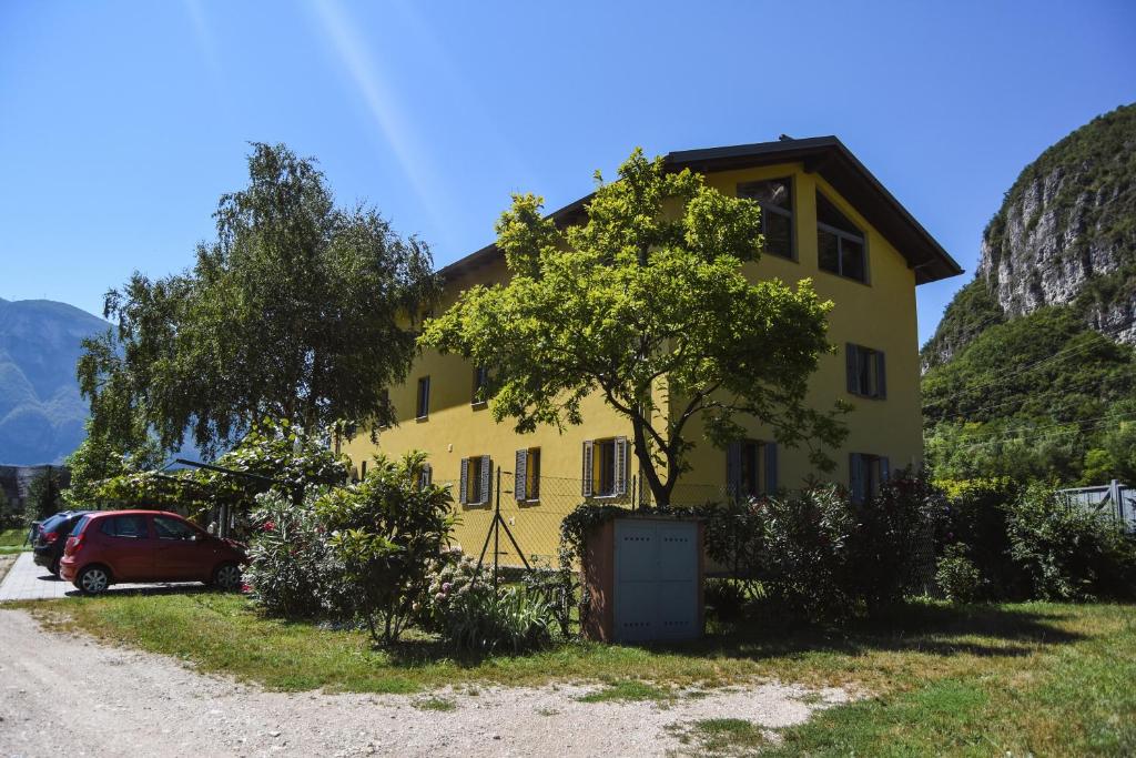 Una casa amarilla con un árbol delante. en Agriturismo La Casa Gialla, en Romagnano