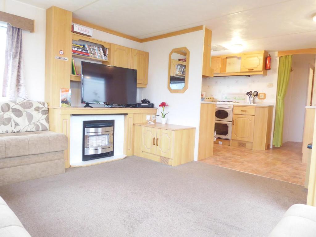 a living room with a fireplace and a tv at Beachside, Family-friendly, WiFi, 8 berth Caravan 158 in Ingoldmells