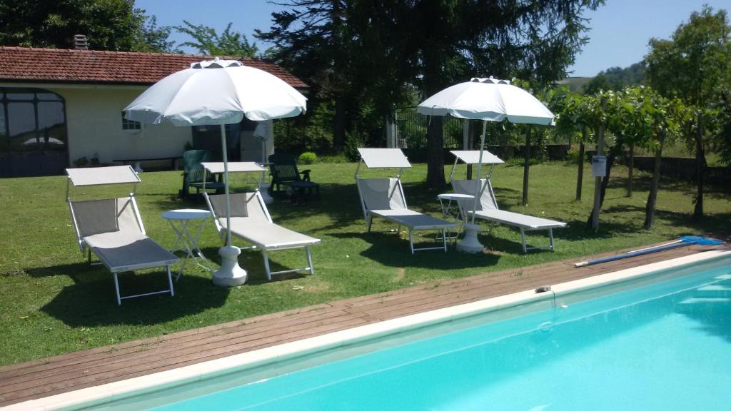 um grupo de cadeiras e guarda-sóis ao lado de uma piscina em Cascina Torello em Dogliani