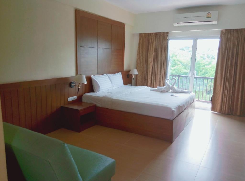 a bedroom with a bed and a chair and a window at The Icon Place 2 @ Nurn Plub Wan in Pattaya