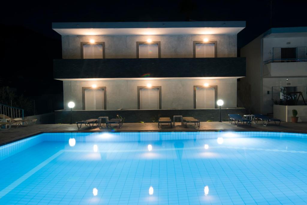 a swimming pool in front of a building at night at Villa Popi Studios (Froso) in Kefalos