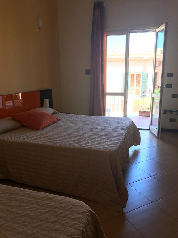 a bedroom with two beds and a sliding glass door at Castellammare Smart Rooms in Castellammare del Golfo