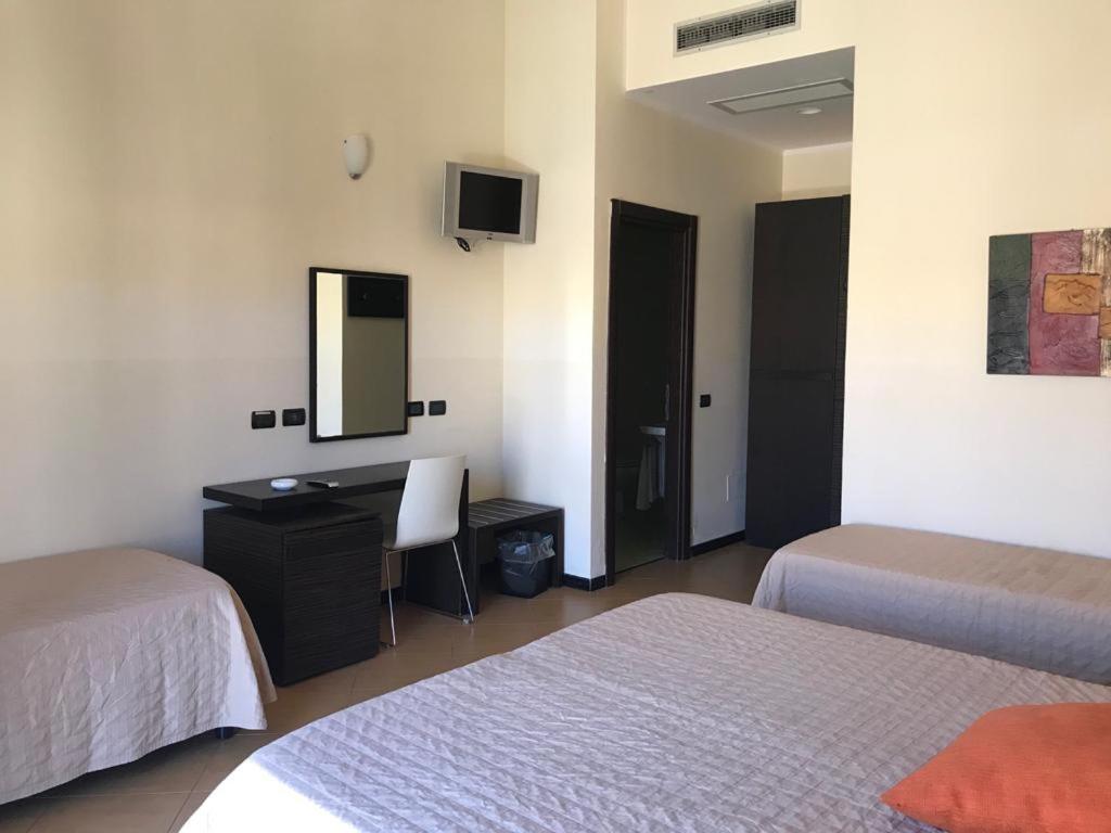 a room with two beds and a desk and a mirror at Castellammare Smart Rooms in Castellammare del Golfo