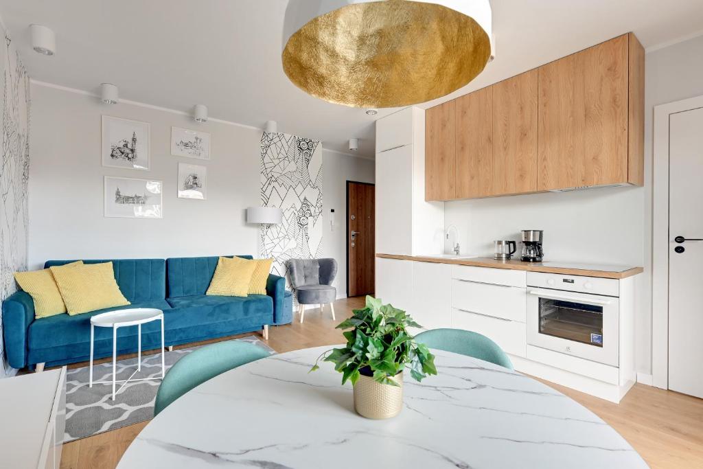 a living room with a blue couch and a table at Wave Apartments - Świętej Barbary 11/60 in Gdańsk