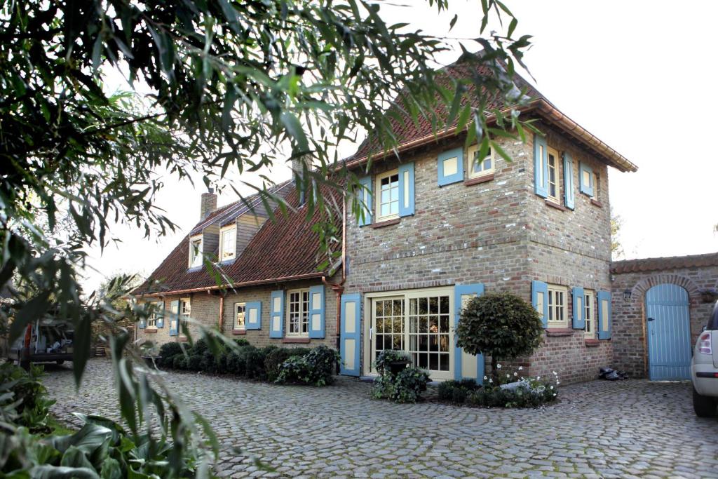 een groot bakstenen huis met blauwe ramen en een oprit bij B&B de Meidoorn in Vinkem