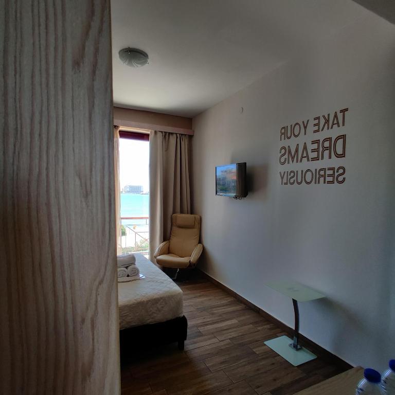 a room with a bed and a chair and a window at City Point Chios in Chios