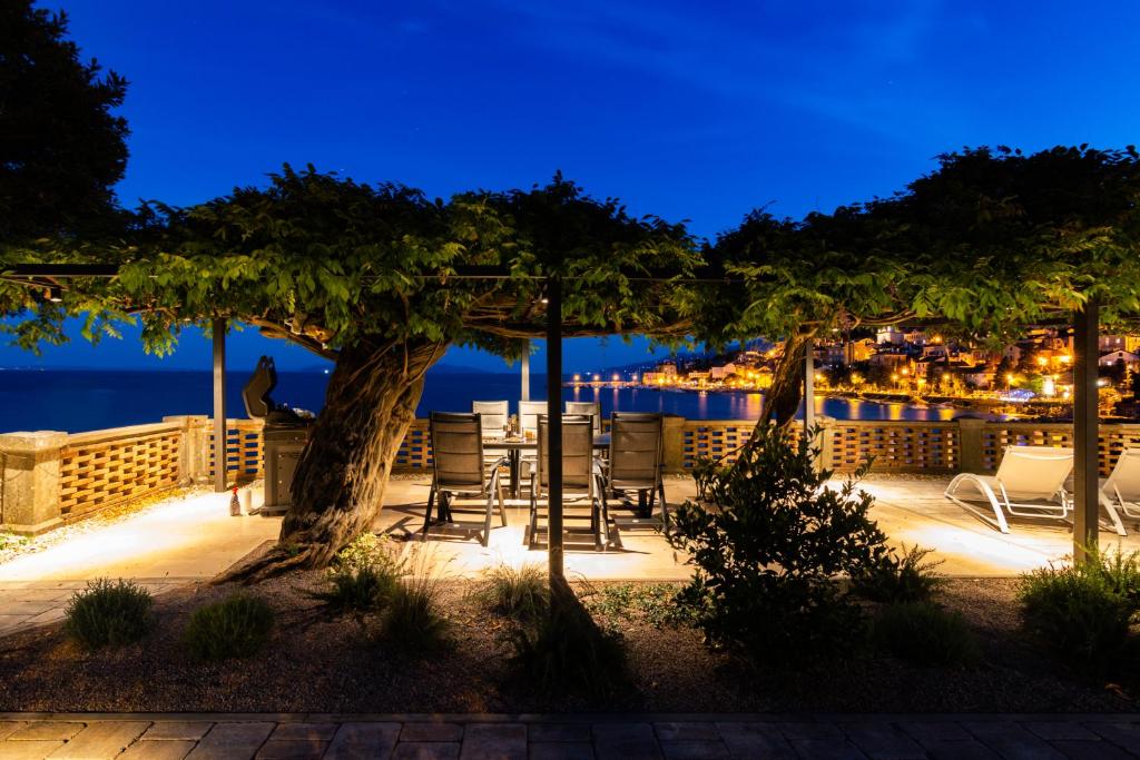 a patio with a table and chairs at night at Seaside Apartment Volosko on the beach in Opatija