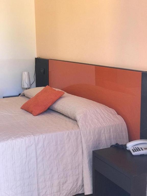 a bedroom with a bed with an orange pillow on it at Castellammare Smart Rooms in Castellammare del Golfo