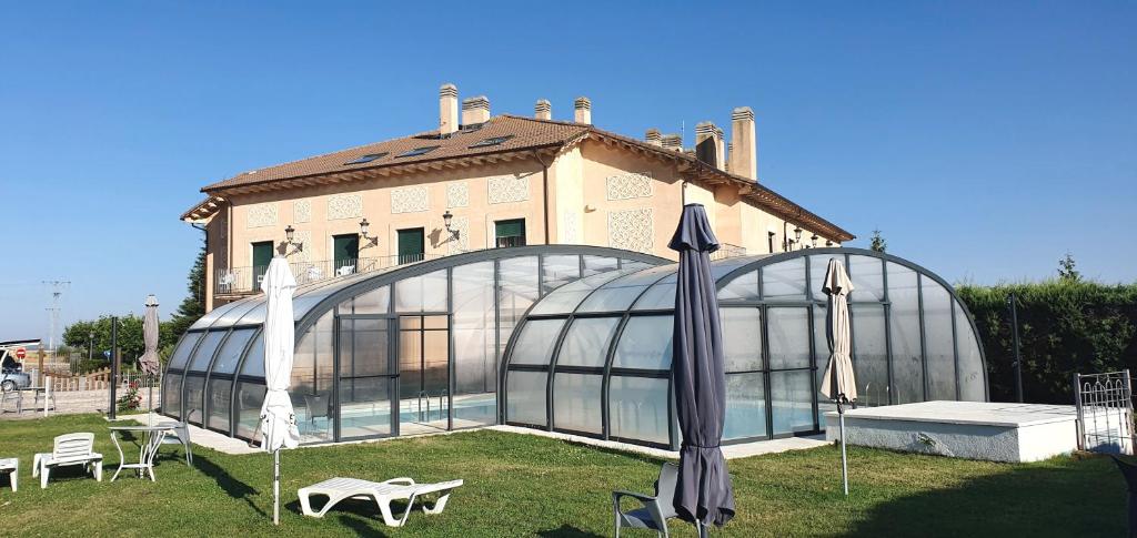 une serre avec deux parasols devant un bâtiment dans l'établissement Mirasierra, à Santo Tomé del Puerto