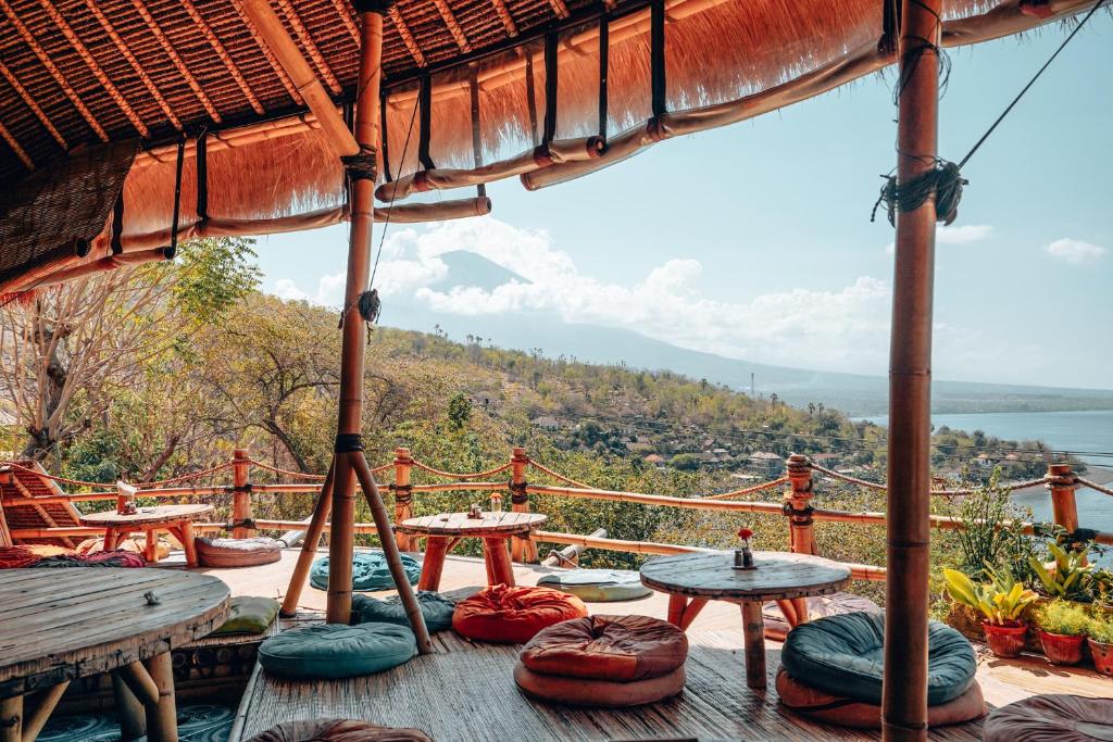 een terras met tafels en stoelen en uitzicht op de oceaan bij Blue Earth Village in Amed
