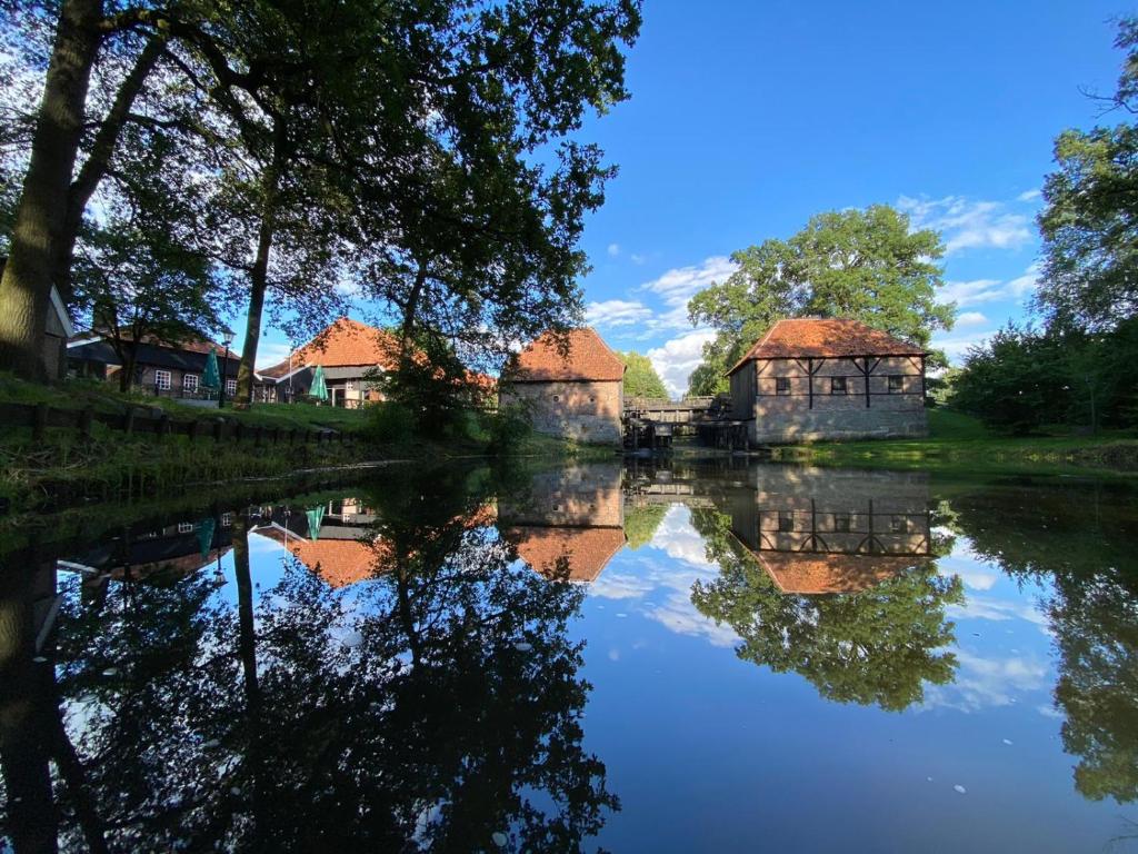 a reflection of two buildings on a river at Hotel de Watermölle in Haaksbergen