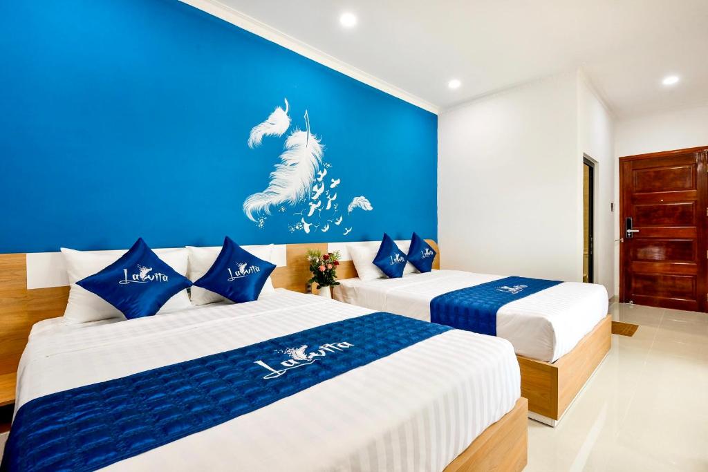 2 łóżka w pokoju z niebieską ścianą w obiekcie La Vita Hotel w mieście Vung Tau