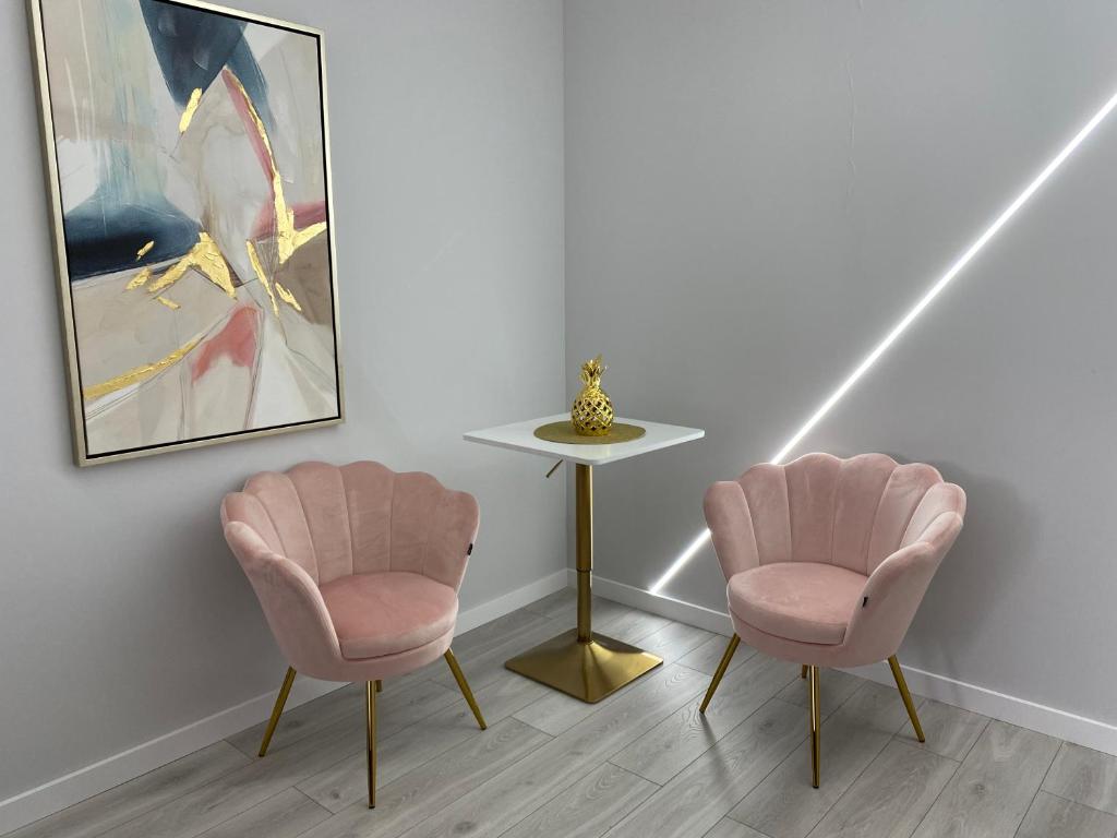 two pink chairs and a table in a room at Novel NeW in Warsaw