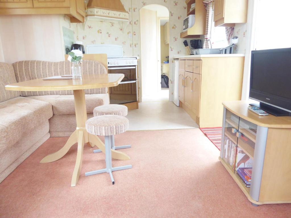 a living room with a table and a kitchen at Beachside, Family-friendly, WiFi, 6 berth Caravan 226 in Ingoldmells