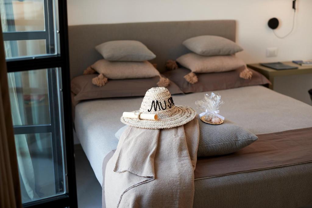 a bed with a hat sitting on top of it at Musae Relais & SPA in Polignano a Mare
