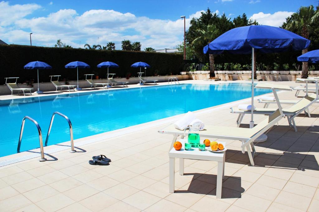 una piscina con sillas, mesa y sombrilla en Residence Oasi Salento, en Torre dell'Orso