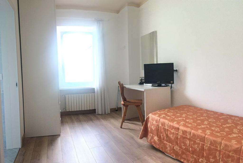 sypialnia z łóżkiem i biurkiem z telewizorem w obiekcie Hotel Juventus w mieście Auronzo di Cadore
