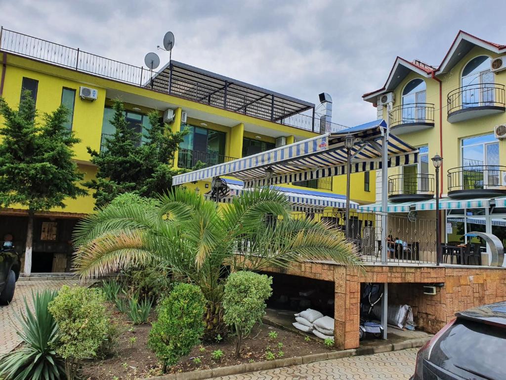 un bâtiment jaune avec des escaliers et des palmiers en face de celui-ci dans l'établissement Delta Hotel, à Ureki