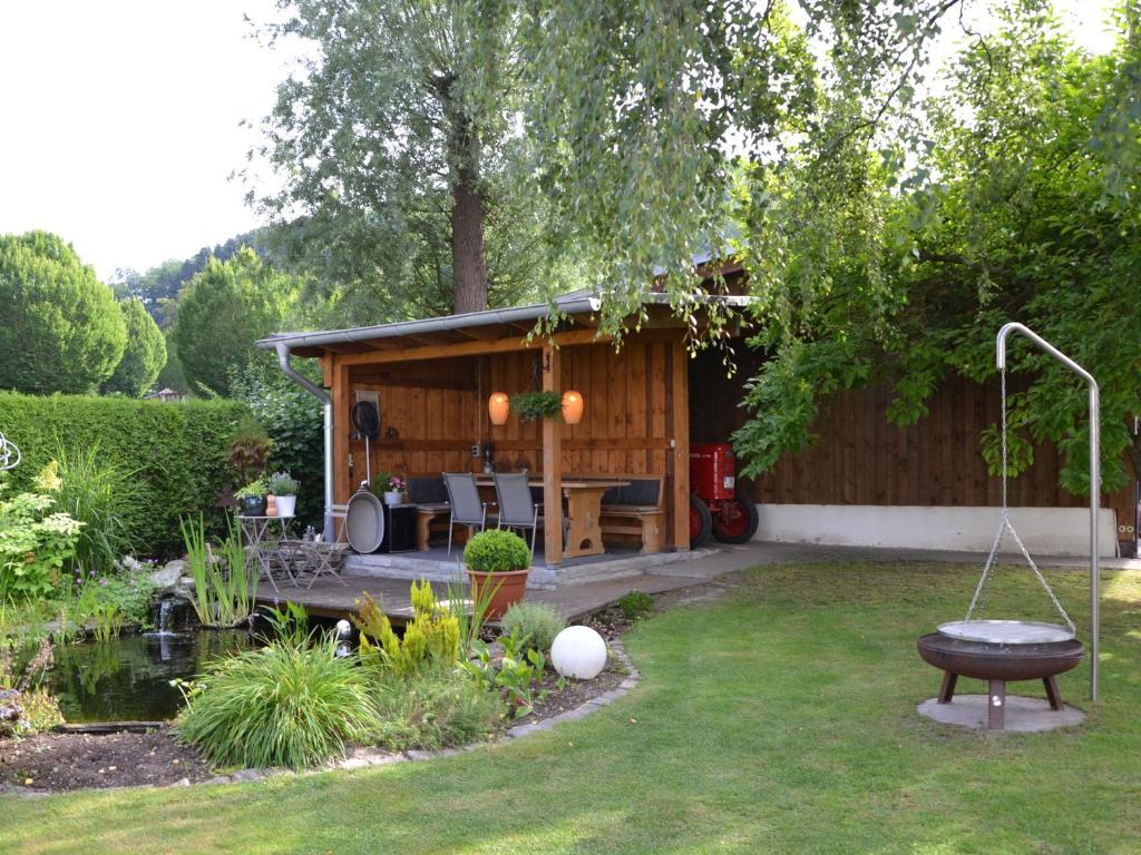 een tuin met een huisje met een tafel en een vijver bij Ferienwohnung Veischedetal im Sauerland in Lennestadt