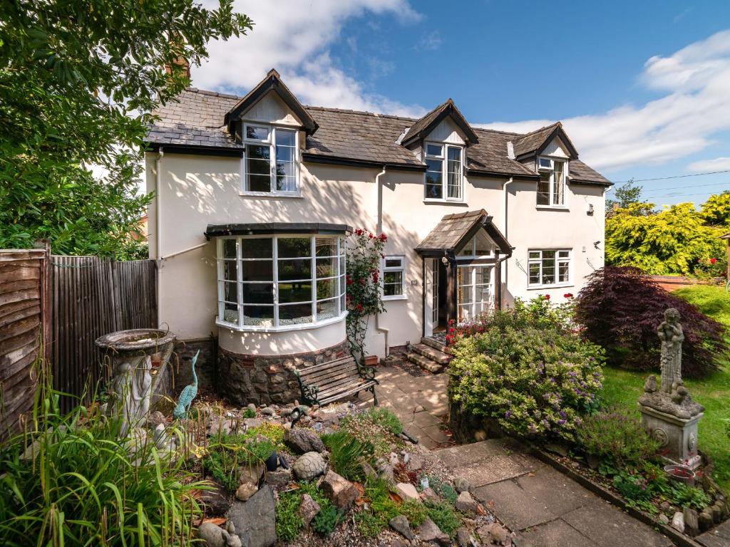 a white house with a fence and a garden at Eleri Cottage in Great Malvern