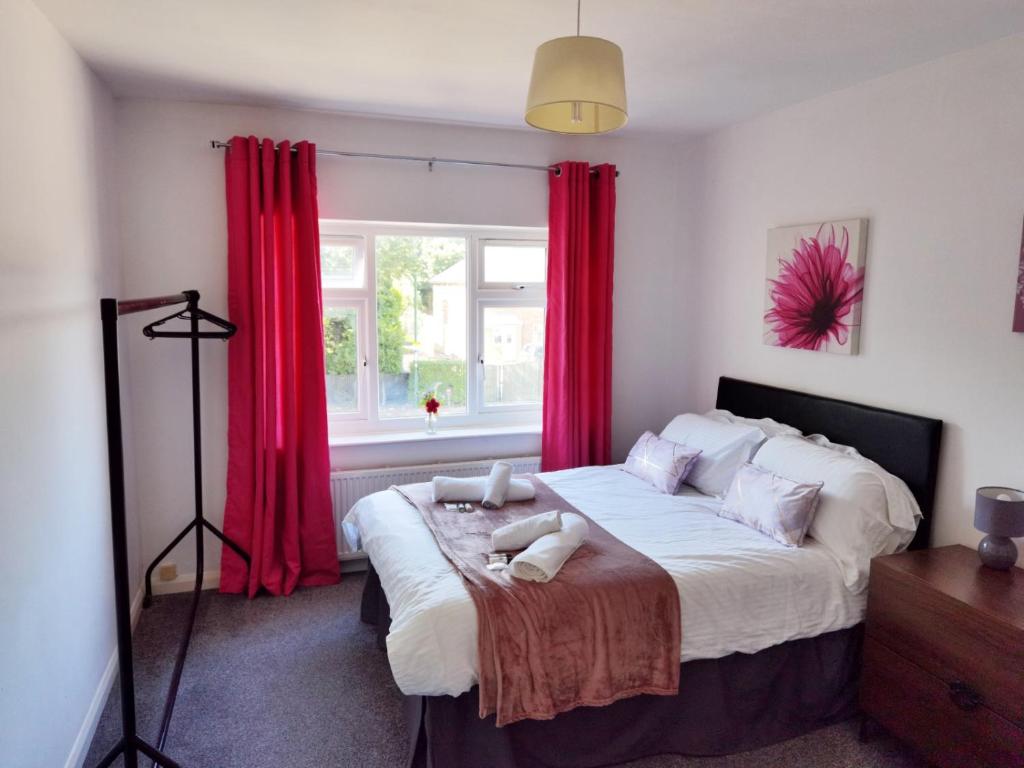 a bedroom with a large bed with red curtains at Perry Road, beautiful large house available for Guests and Contractors Parking wifi in Nottingham