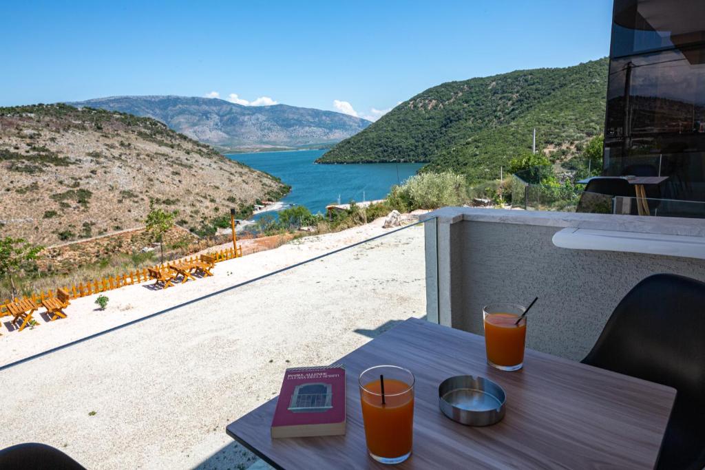 a table with two glasses of orange juice on a balcony at Inada Hotel Ksamil in Ksamil