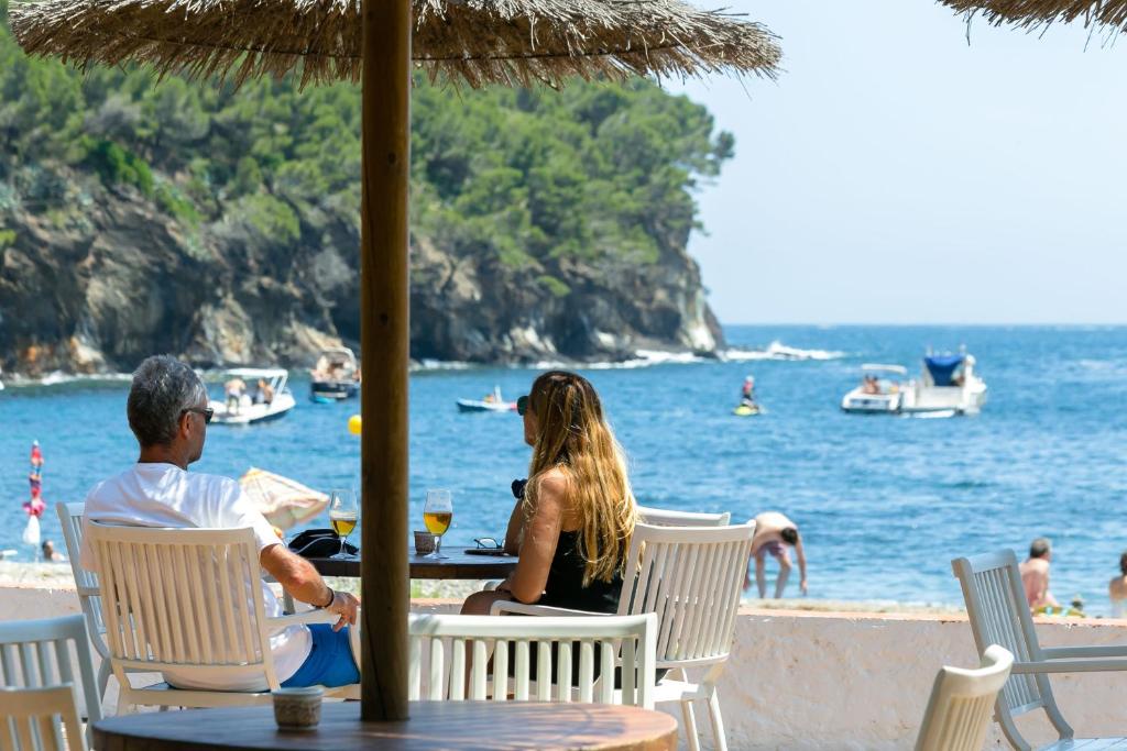 um homem e uma mulher sentados numa mesa na praia em Ciudad De Vacaciones Cala Montjoi em Roses