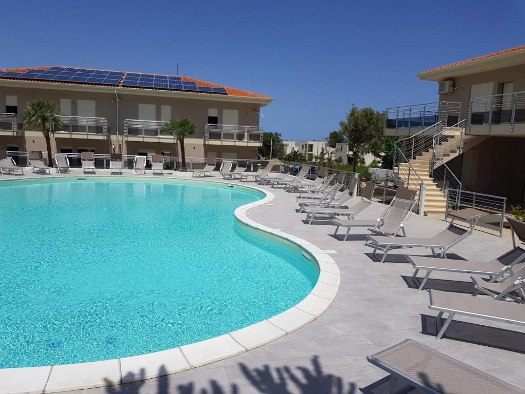 a swimming pool with lounge chairs and a building at Appartamento Miele in Zambrone