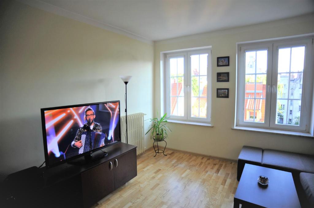 ein Wohnzimmer mit einem Flachbild-TV auf einem Stand in der Unterkunft Długa Street Apartament in Danzig