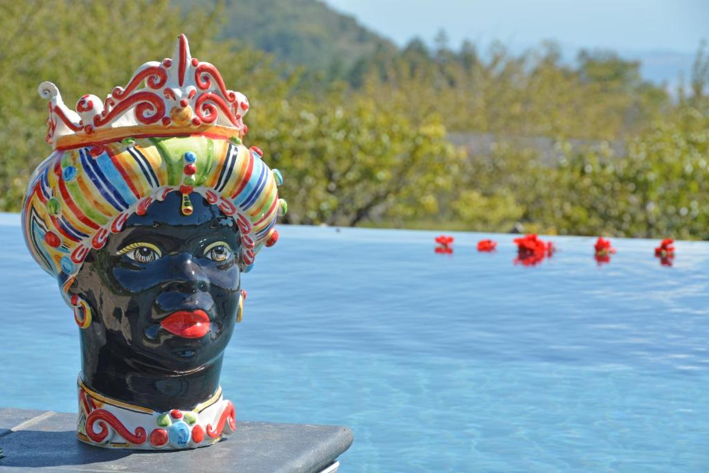 una estatua con una corona en la cabeza junto a una piscina en Cirasa Luxury Country House, en Trecastagni