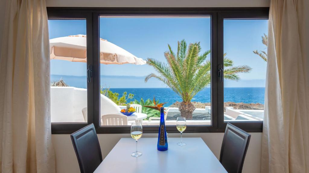 a table with wine glasses and a view of the ocean at Reyes Natur in Charco del Palo